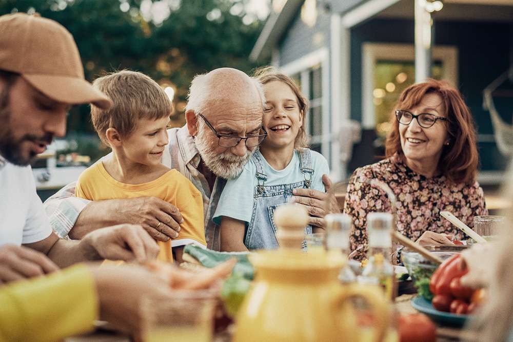 A family sits and eats together outside in the yard